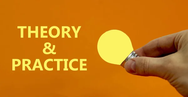 Theory and practice symbol. Businessman holds yellow shining light bulb. Words \'Theory and practice\'. Beautiful orange background. Light bulb icon. Business, theory and practice concept. Copy space.