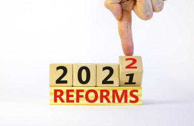 2022 reformunun yeni yıl planlama sembolü. İşadamı ahşap küpü değiştiriyor ve '2021 reformları' 2022 reformlarına çeviriyor. Güzel beyaz arka plan, kopyalama alanı. İş dünyası, 2022 reform kavramı.