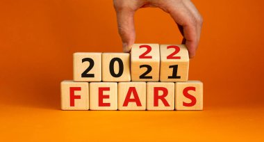 2022 yılbaşı sembolünden korkuyor. İş adamı ahşap küpleri değiştirip '2021 Korkular 2022' olarak değiştiriyor. Güzel turuncu arkaplan, kopyalama alanı. İş dünyası, 2022 yeni yıl kavramından korkuyor.
