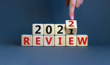 2022 Yeni Yıl Sembolü. İşadamı ahşap bir küpü çevirir ve 'İnceleme 2021' i 'İnceleme 2022' olarak değiştirir. Güzel gri arkaplan, kopyalama alanı. İş, 2022 Yeni Yıl Konsepti.