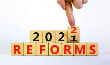 2022 reformunun yeni yıl planlama sembolü. İşadamı ahşap küpü değiştiriyor ve '2021 reformları' 2022 reformlarına çeviriyor. Güzel beyaz arka plan, kopyalama alanı. İş dünyası, 2022 reform kavramı.