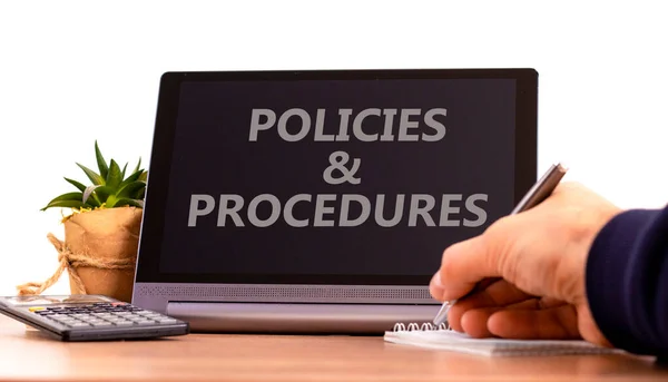 Policies and procedures symbol. Tablet with words \'Policies and procedures\'. Businessman hand with pen, house plant. Beautiful white background. Business, policies and procedures concept, copy space.