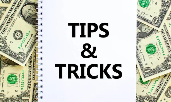 Tips and tricks symbol. Words \'Tips and tricks\' on white note. Beautiful background from dollar bills. Business, tips and tricks concept. Copy space.