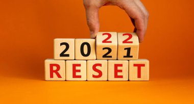 2022 yeni yıl sembolünü sıfırladı. İşadamı ahşap küpleri değiştiriyor ve '2021' i sıfırla 'yı' 2022 'ye sıfırla' olarak değiştiriyor. Güzel turuncu arkaplan, kopyalama alanı. İş, 2022 Yeni Yıl Konseptini Sıfırla.