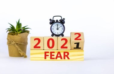 2022 yılbaşı sembolünden korkuyor. Çalar saat. Tahta bir küp yaptı, 'Fear 2021' kelimesini 'Fear 2022' olarak değiştirdi. Güzel beyaz arka plan, kopyalama alanı. İş dünyası, 2022 Yeni yıl konseptinden korkuyor.