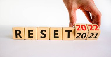 2022 yeni yıl sembolünü sıfırladı. İşadamı ahşap küpleri değiştiriyor ve '2021' i sıfırla 'yı' 2022 'ye sıfırla' olarak değiştiriyor. Güzel beyaz arka plan, kopyalama alanı. İş, 2022 Yeni Yıl Konseptini Sıfırla.