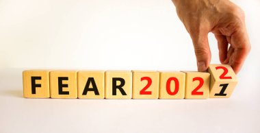 2022 yılbaşı sembolünden korkuyor. İş adamı ahşap küpü değiştirip 'Fear 2021' i 'Fear 2022' olarak değiştiriyor. Güzel beyaz arka plan, kopyalama alanı. İş dünyası, 2022 Yeni yıl konseptinden korkuyor.