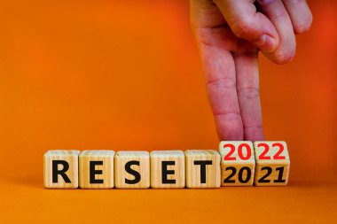 2022 yeni yıl sembolünü sıfırladı. İşadamı ahşap küpleri değiştiriyor ve '2021' i sıfırla 'yı' 2022 'ye sıfırla' olarak değiştiriyor. Güzel turuncu arkaplan, kopyalama alanı. İş, 2022 Yeni Yıl Konseptini Sıfırla.