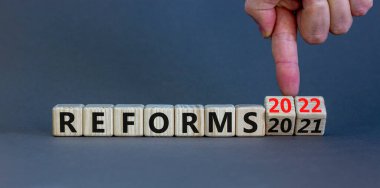 2022 reformları yeni yıl sembolü. İşadamı ahşap küpü değiştiriyor ve '2021 reformları' 2022 reformlarına çeviriyor. Güzel gri arkaplan, kopyalama alanı. İş, 2022 Reformlar Yeni Yıl Konsepti.