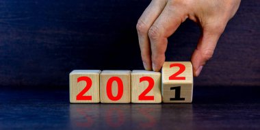 2022 mutlu yeni yıl sembolü. İş adamı küpü çevirir, 2021 'den 2022' ye olan değişimi sembolize eder. Güzel siyah arka plan. Uzayı kopyala İş ve 2022 Mutlu yıllar konsepti.