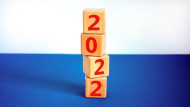 2022 mutlu yeni yıl sembolü. Tahta küpler 2021 'den yeni yıla 2022' ye geçişi sembolize eder. Güzel beyaz ve mavi arka plan. Uzayı kopyala İş ve 2022 Mutlu yıllar konsepti.