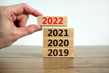 2022 mutlu yeni yıl sembolü. İşadamı '2022' numarasıyla bir blok tutuyor. 2019, 2020, 2021 numaralarıyla dolu. Güzel beyaz arka plan. Uzayı kopyala İş dünyası, 2022 Mutlu yıllar konsepti.