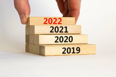 2022 mutlu yeni yıl sembolü. İşadamı '2022' numarasıyla bir blok tutuyor. 2019, 2020, 2021 numaralarıyla dolu. Güzel beyaz arka plan. Uzayı kopyala İş dünyası, 2022 Mutlu yıllar konsepti.