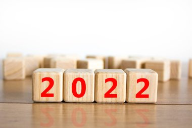 2022 mutlu yeni yıl sembolü. Tahta küpler 2021 'den yeni yıla 2022' ye geçişi sembolize eder. Güzel beyaz arka plan. Uzayı kopyala İş ve 2022 Mutlu yıllar konsepti.