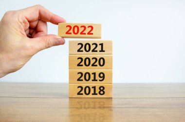 2022 mutlu yeni yıl sembolü. İşadamı '2022' numarasıyla bir blok tutuyor. 2018, 2019, 2020, 2021 numaralarıyla dolu. Güzel beyaz arka plan. Uzayı kopyala İş dünyası, 2022 Mutlu yıllar konsepti.