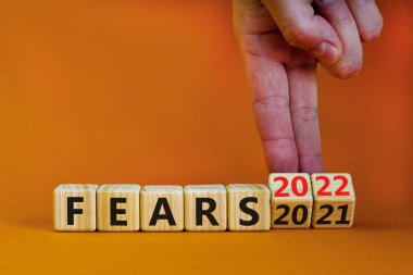 2022 yılbaşı sembolünden korkuyor. İş adamı ahşap küpleri değiştirip '2021 Korkular 2022' olarak değiştiriyor. Güzel turuncu arkaplan, kopyalama alanı. İş dünyası, 2022 yeni yıl kavramından korkuyor.