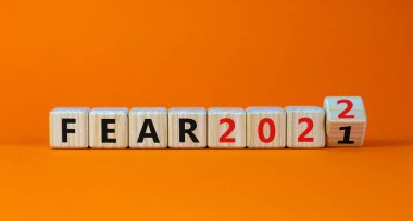 2022 yılbaşı sembolünden korkuyor. Tahta bir küp yaptı ve 'Fear 2021' kelimesini 'Fear 2022' olarak değiştirdi. Güzel turuncu arkaplan, kopyalama alanı. İş dünyası, 2022 Yeni yıl konseptinden korkuyor.