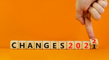 2022 'nin planlanması yeni yıl sembolünü değiştirir. İşadamı ahşap küpü çeviriyor ve 2021 Değişiklikleri 2022 olarak değiştiriyor. Güzel turuncu arkaplan, kopyalama alanı. İş, 2022 Yeni Yıl Konseptini Değiştiriyor.