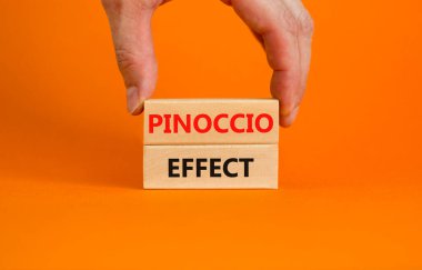 Pinokyo etkisi sembolü. Güzel bir turuncu arka plandaki tahta bloklar üzerinde Pinokyo etkisi. İşadamı eli. İş ve Pinokyo etkisi kavramı, kopyalama alanı.