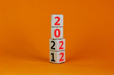 2022 mutlu yeni yıl sembolü. Küplere dönüştürülmüş, 2021 'den 2022' ye olan değişimi sembolize ediyor. Güzel turuncu arka plan. Uzayı kopyala İş ve 2022 Mutlu yıllar konsepti.