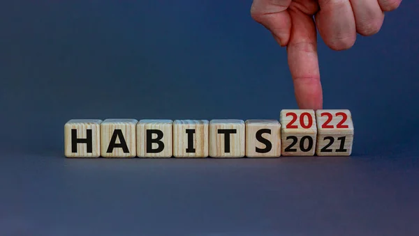 2022 habits and new year symbol. Businessman turns wooden cubes and changes words 'habits 2021' to 'habits 2022'. Beautiful grey background, copy space. Business, 2022 habits and new year concept.