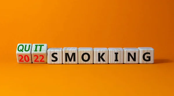 Quit smoking 2022 new years resolution symbol. Turned wooden cubes with words '2022 quit smoking'. Beautiful orange background, copy space. Healthy lifestyle and 2022 quit smoking concept.