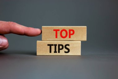 Üst uç sembolü. Güzel gri bir arka planda tahta bloklardaki en üst uç kavramsal kelimeler. İşadamı eli. İş ve Üst İpuçları konsepti, kopyalama alanı.