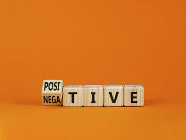 Pozitif ya da negatif sembol. Tahta bir küpü, 'negatif' kelimesini 'pozitif' olarak değiştirdi. Güzel turuncu masa, turuncu arka plan, fotokopi alanı. İş, pozitif ya da olumsuz kavram.