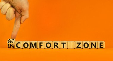 Dışarı ya da güvenli bölge sembolü. İş adamı ahşap bir küpü çevirir ve 'güvenli bölgede' kelimesini 'konfor bölgesi' olarak değiştirir. Güzel turuncu arkaplan, kopyalama alanı. İş, psikoloji konsepti.