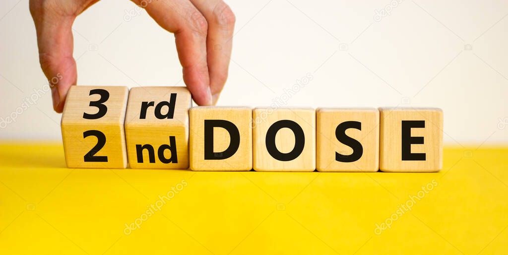 Covid-19 booster dose vaccine shot symbol. Doctor turns cubes and changes words '2nd dose' to '3rd dose'. Beautiful white background, copy space. Covid-19 booster dose vaccine shot concept.