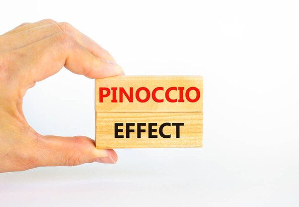 Pinoccio effect symbol. Concept words Pinoccio effect on wooden blocks on a beautiful white background. Businessman hand. Business and Pinoccio effect concept, copy space.