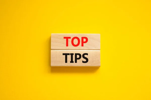 Top tips symbol. Concept words Top tips on wooden blocks on a beautiful yellow background. Business and Top tips concept, copy space.