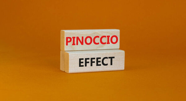 Pinoccio effect symbol. Concept words Pinoccio effect on wooden blocks on a beautiful orange background. Business and Pinoccio effect concept, copy space.