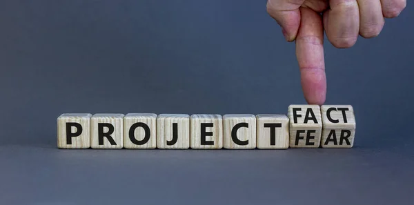 Project fact or fear symbol. Businessman turns cubes, changes words \'project fear\' to \'project fact\'. Beautiful grey background. Business, ecological and project fact or fear concept. Copy space.