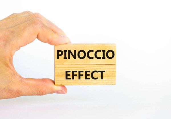 Pinoccio effect symbol. Concept words Pinoccio effect on wooden blocks on a beautiful white background. Businessman hand. Business and Pinoccio effect concept, copy space.