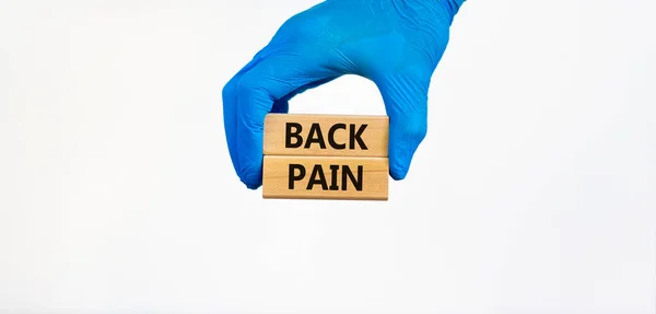 腰痛のシンボル 青い手袋の医師の手は言葉で木製のブロックを保持背中の痛み 美しい白い背景 医学的および腰痛の概念 — ストック写真