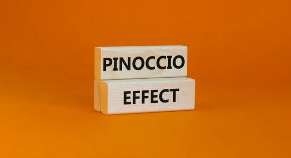 Pinoccio effect symbol. Concept words Pinoccio effect on wooden blocks on a beautiful orange background. Business and Pinoccio effect concept, copy space.