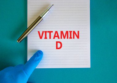 D vitamini sembolü. D vitamini, güzel mavi arkaplan, doktor eli mavi eldiven ve metalik kalem içeren beyaz bir not. Tıbbi, D vitamini konsepti.
