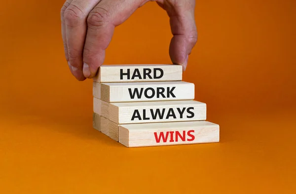 努力工作总能赢得象征 在漂亮的橙色背景上的木块上 努力工作总能赢 的概念词 商人的手 激励和努力工作总能赢得理念 — 图库照片