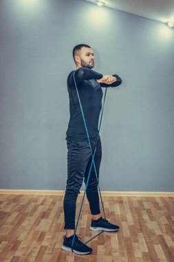 Dikey, tam boy, ilmek bantlı sporcu idmanı, ayaklı ve kollu esnek direnç ipi, yanlamasına kararlı ve ciddi, fitness eğitimi.