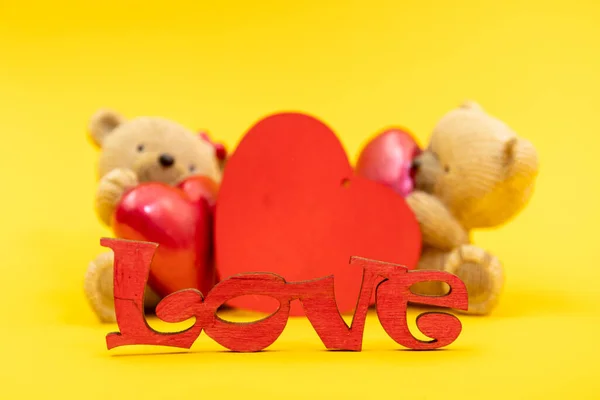 Couple of teddy bears toys and the word love from wooden letters, red hearts. Valentine day concept. Postcard template.