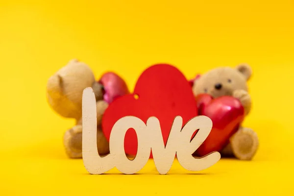 Couple of teddy bears toys and the word love from wooden letters, red hearts. Valentine day concept. Postcard template.