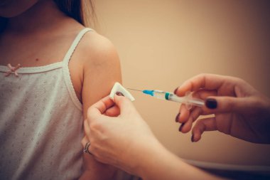 Doktor, çocuk koronavirüsü ve diğer salgın hastalıkları durdurmak için aşı yapıyor. Covid-19 Corona virüsüne karşı kavramsal mücadele. Bir kadının elinde şırınga.