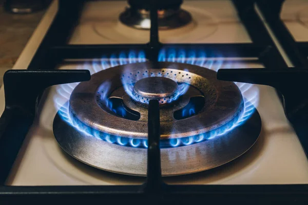 Burning blue gas. Focus on the front edge of the gas burners. Flame burning from a kitchen gas stove. Energy save concept.