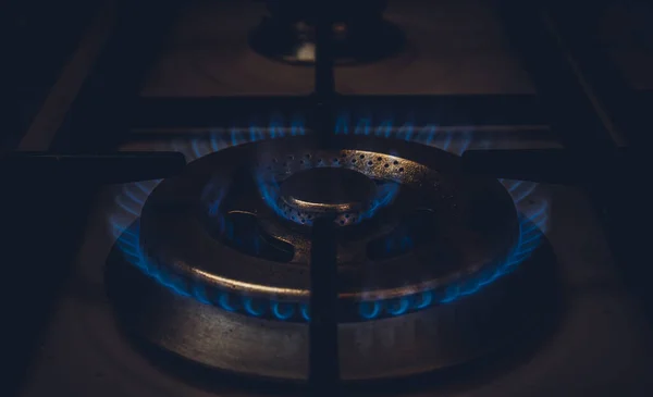 Burning blue gas. Focus on the front edge of the gas burners. Flame burning from a kitchen gas stove. Energy save concept.
