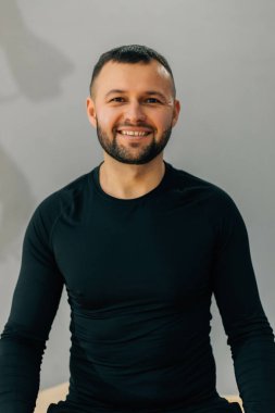 Gri arka planda elleri çapraz olan kendine güvenen sakallı bir adam..