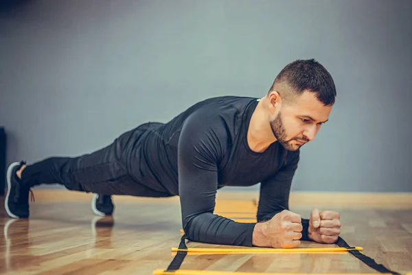 Fitness training athletic sporty man doing plank exercise in gym or home concept. Bearded man exercising workout aerobic at grey background.