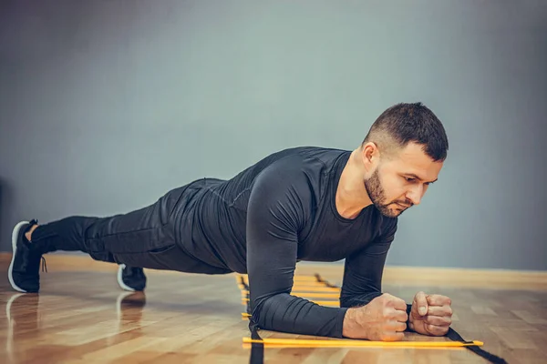 Fitness training athletic sporty man doing plank exercise in gym or home concept. Bearded man exercising workout aerobic at grey background.
