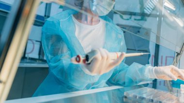 Bilim adamları numuneleri tutar ve inceler. Cam cuvette içine odaklanmış kadın bilim profesyonel pipet çözeltisi. Lensler pipete odaklanıyor. Sağlık ve biyoteknoloji..