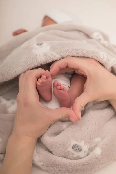 在新生婴儿的脚周围 母亲的手呈心形 用双手把婴儿的脚紧紧地抱在怀里 — 图库照片